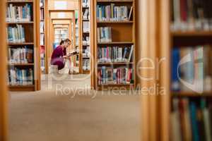 Young woman reading book in library