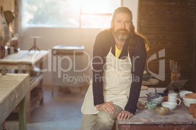 Portrait of male potter sitting on table