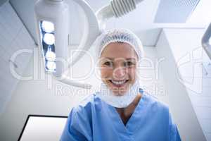 Dental assistant smiling at camera beside light