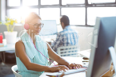 Business executive listening to music while working on computer Business executive listening to music while working on computer