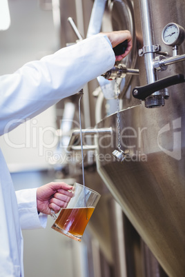 Manufacturer filling beer into glass at brewery