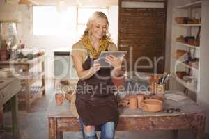 Beautiful female potter using digital tablet