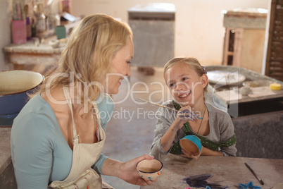 Female potter interacting with girl in pottery workshop