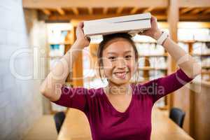 Portrait of young woman carrying book on head