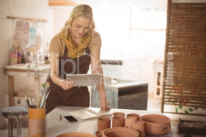 Female potter using digital tablet while working