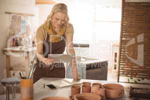 Female potter using digital tablet while working