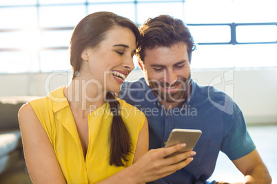 Female business executive showing mobile phone to co-worker