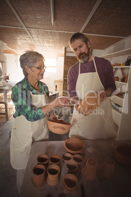 Male and female potter interacting while examining a pot