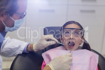 Dentist examining a young patient with tools