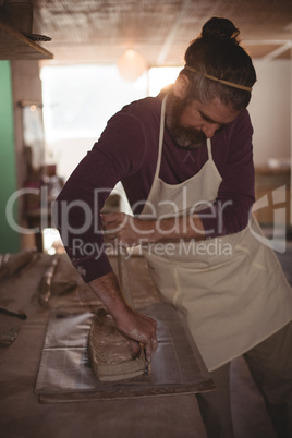Male potter designing clay with stick