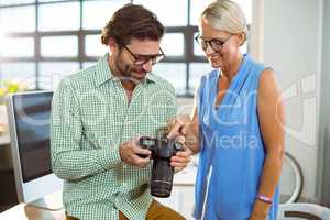 Graphic designer showing photo to colleague on digital camera