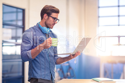 Business executive having coffee and looking at laptop