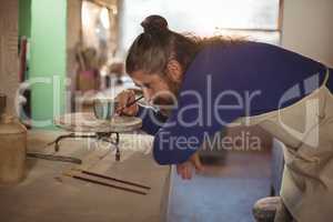 Attentive male potter painting on bowl