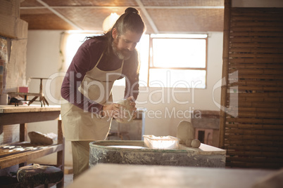 Male potter putting clay pottery wheel in pottery workshop