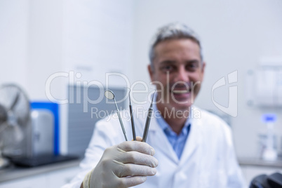 Portrait of smiling dentist holding dental tools