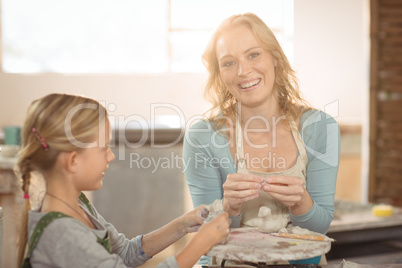 Smiling female potter assisting girls