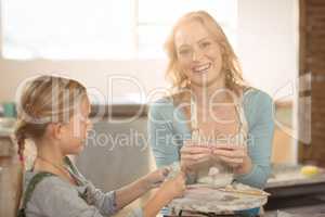 Smiling female potter assisting girls