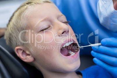 Dentist examining a young patient with tools