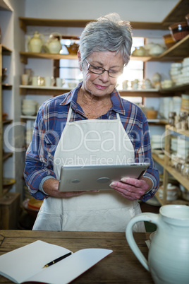 Attentive female potter using digital tablet