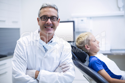 Portrait of smiling dentist standing with arms crossed