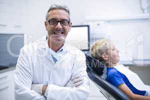 Portrait of smiling dentist standing with arms crossed
