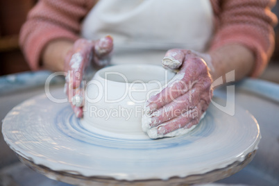 Mid section of female potter making pot