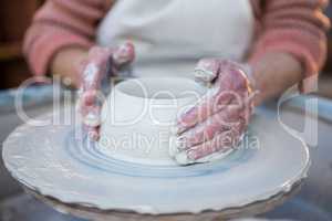 Mid section of female potter making pot