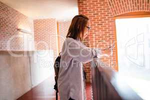 Young woman using mobile phone in corridor