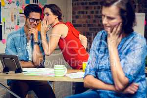 Businesswoman in deep thought and colleagues whispering in backg