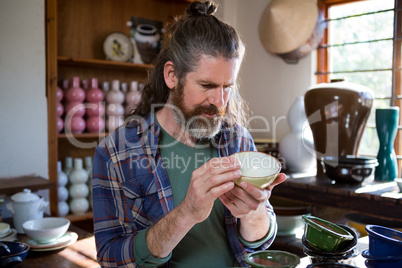 Male potter checking bowl