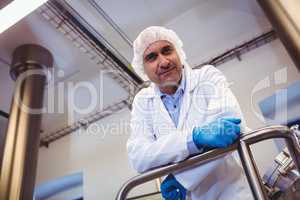 Smiling manufacturer leaning on pipe at brewery