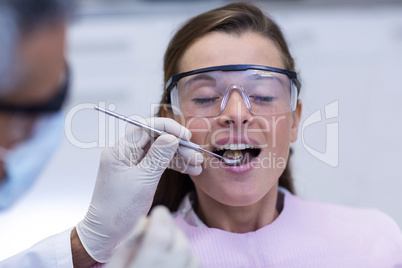 Dentist examining a female patient with tools