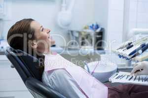 Dentist picking up dental tools to examine a female patient