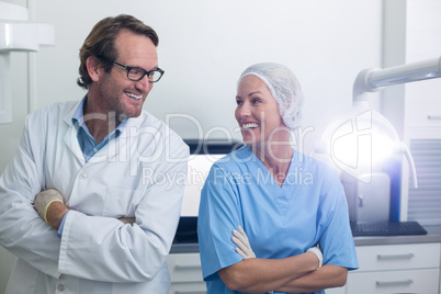 Smiling dentist and dental assistant standing with arms crossed