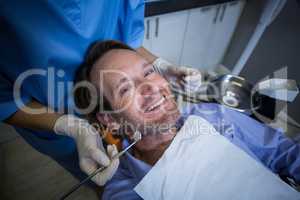 Dentist examining a young patient with tools