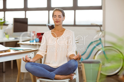 Woman sitting on chair and performing yoga