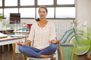 Woman sitting on chair and performing yoga