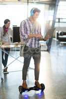 Smiling man standing on hoverboard and using laptop
