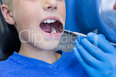 Dentist examining a young patient with tools