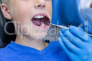 Dentist examining a young patient with tools