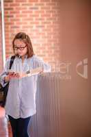 Young woman using mobile phone in corridor