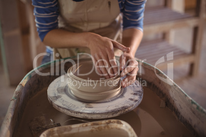 Mid section of female potter making pot