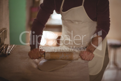 Male potter molding clay with rolling pin