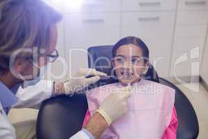 Dentist examining a young patient with tools