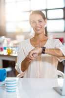 Business executive sitting on chair and adjusting a smartwatch