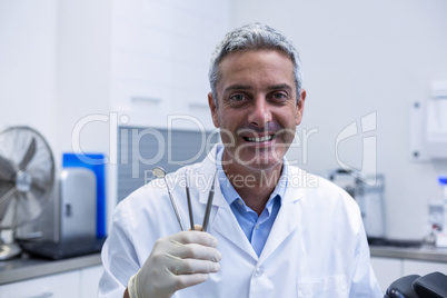 Portrait of smiling dentist holding dental tools