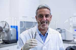 Portrait of smiling dentist holding dental tools