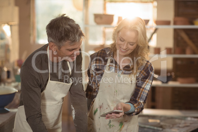 Potters showing mobile phone in pottery workshop