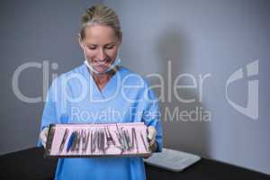Dental assistant holding tray with equipment in dental clinic