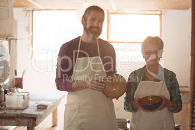 Male and female potter holding earthenware pots